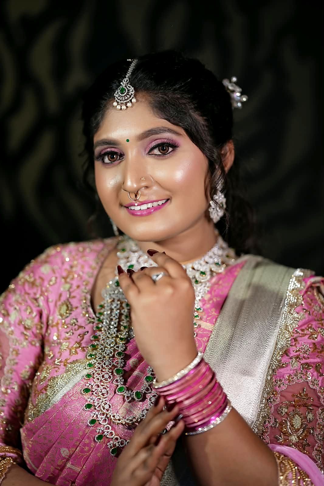 Close-up studio portrait with pink eyeshadow, glowing skin and pink lips, styled with emerald-and-diamond jewellery